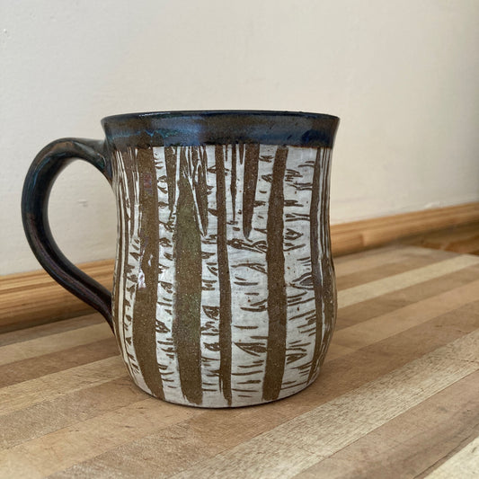 Ceramic mug with a nature-themed design on a wooden surface