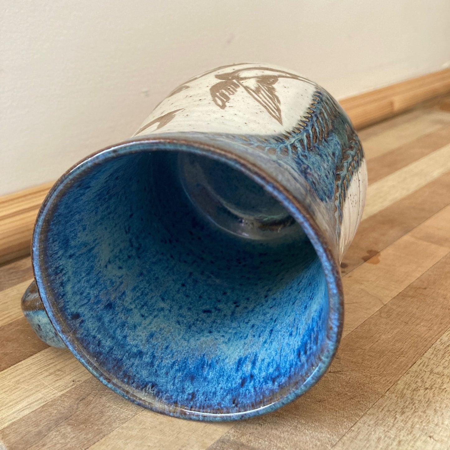Ceramic mug with blue interior on a wooden surface