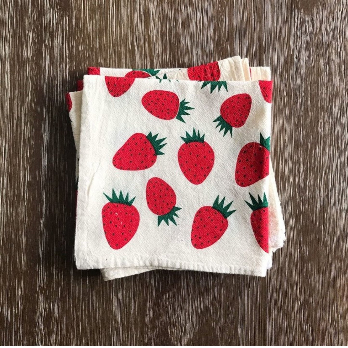 Folded towel with strawberry pattern on a wooden surface
