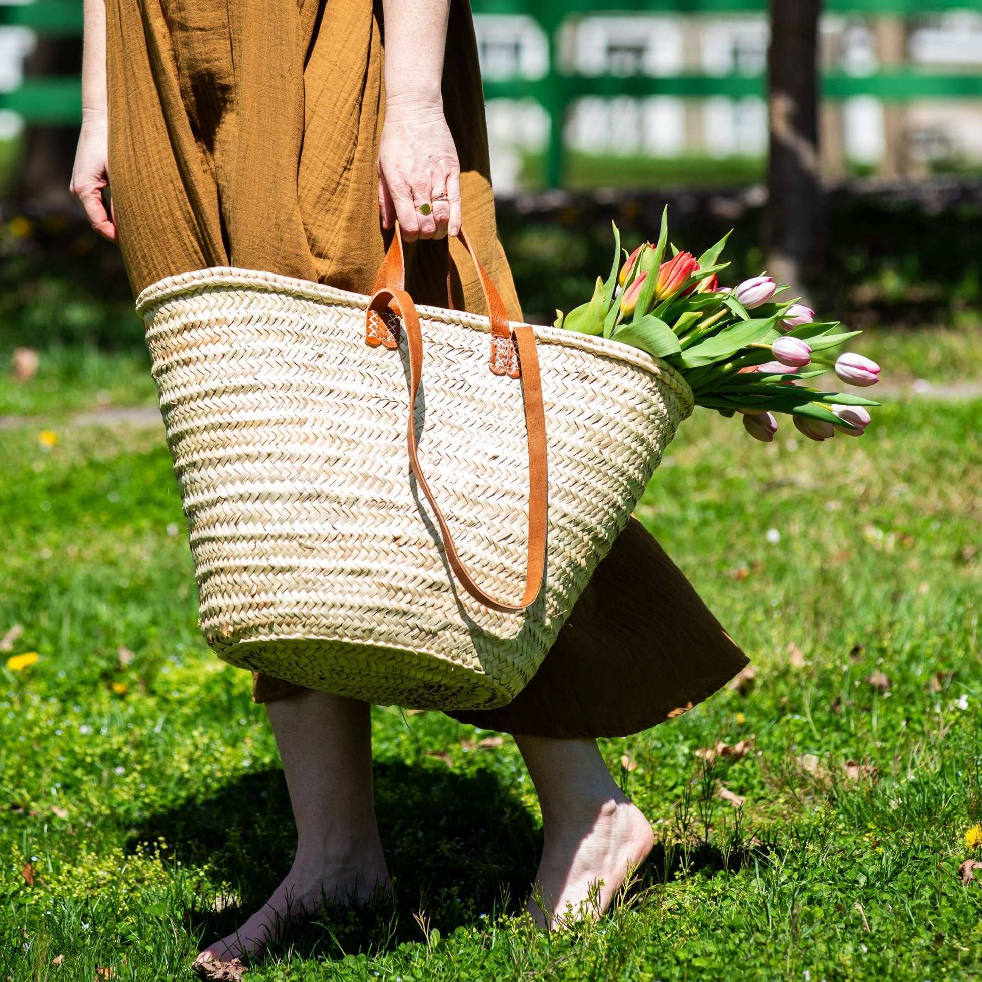 A woman carrying a french market tote bag with leather straps