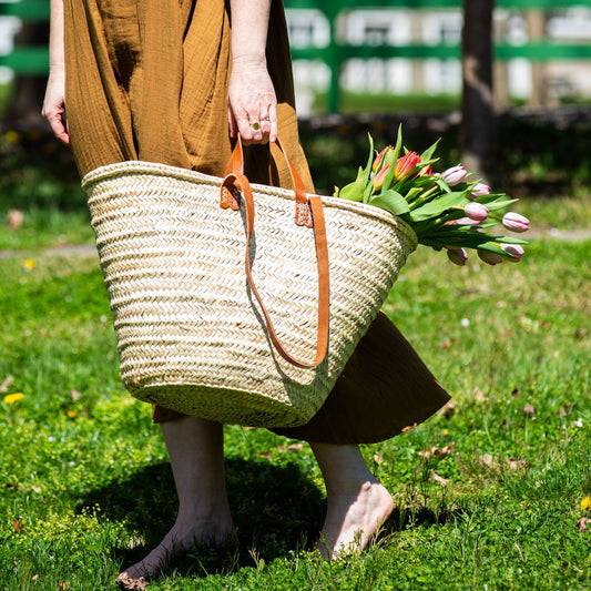 A woman carrying a french market tote bag with leather straps