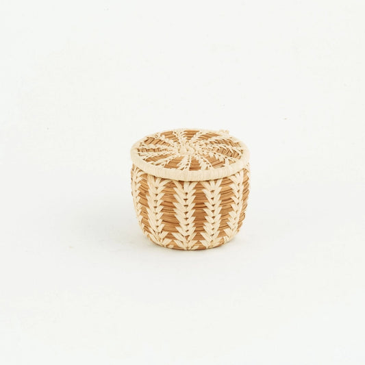 Brown and tan miniature pine needle basket with lid on and an intricate raffia design.