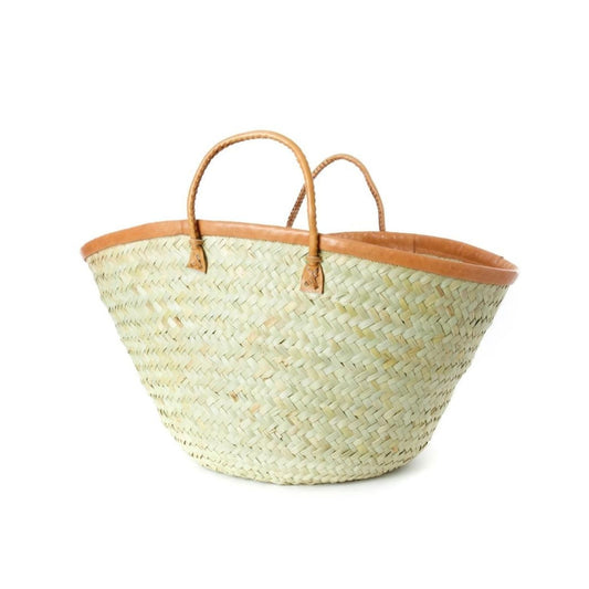 A woven palm fiber tote basket with tan leather handles.