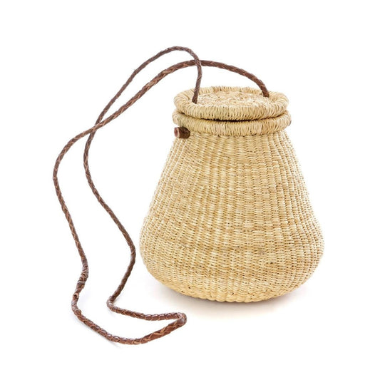 Lidded crossbody pear-shaped basket bag with a brown leather braided strap.