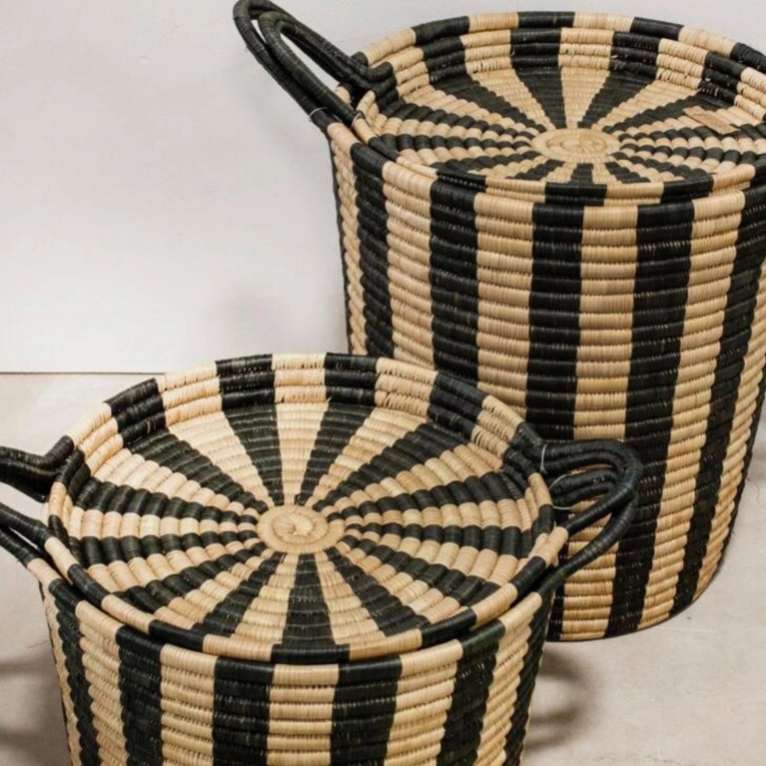 Closer picture from above of black and tan striped storage baskets in large and small with tray lids.