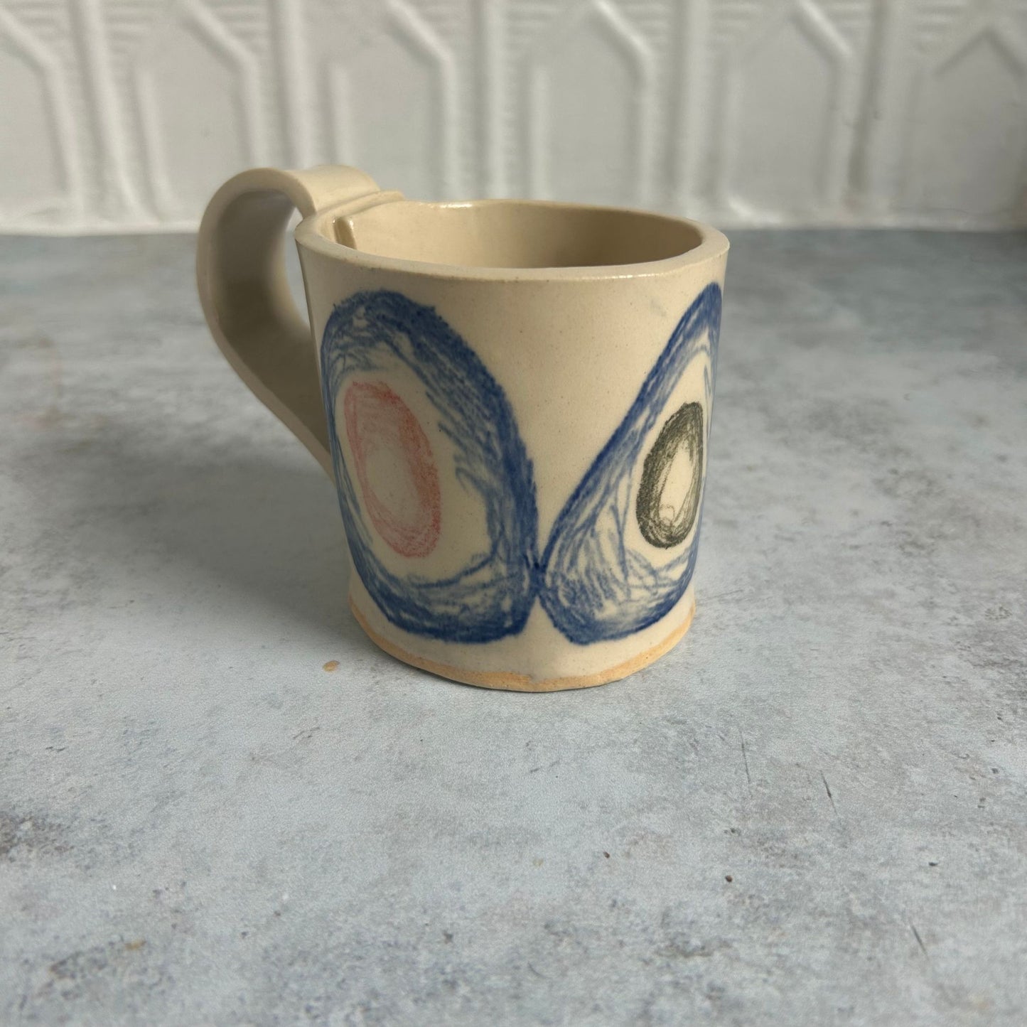 A white mug with blue circles and red and green smaller circles within each blue one.