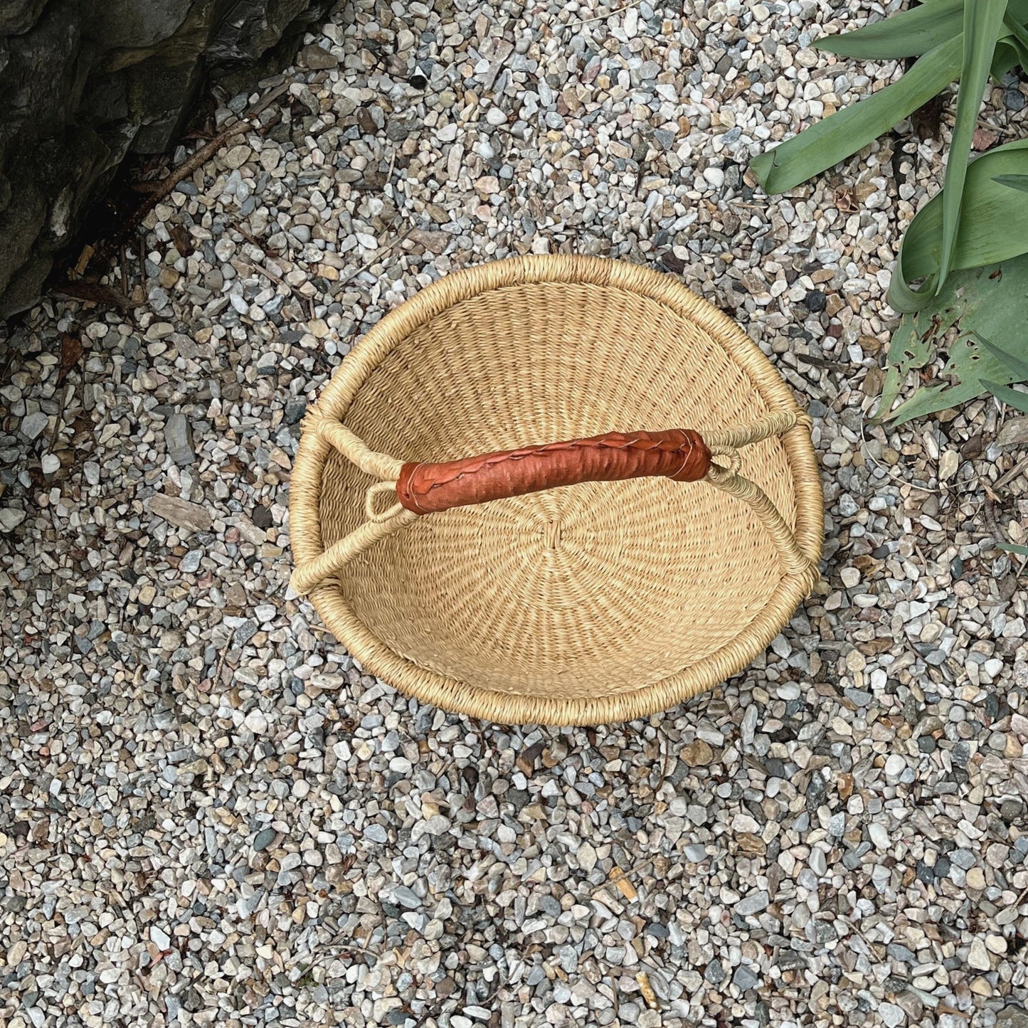Above view of the flat bottomed fruit basket sitting outside on pebbles.