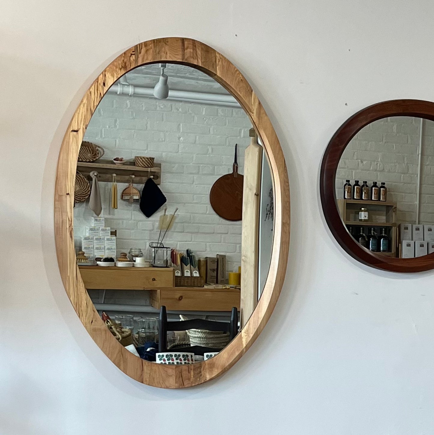 various sizes of hand-carved wooden wall mirrors each with one-of-a-kind organic shape and curves shown in butternut cherry and walnut
