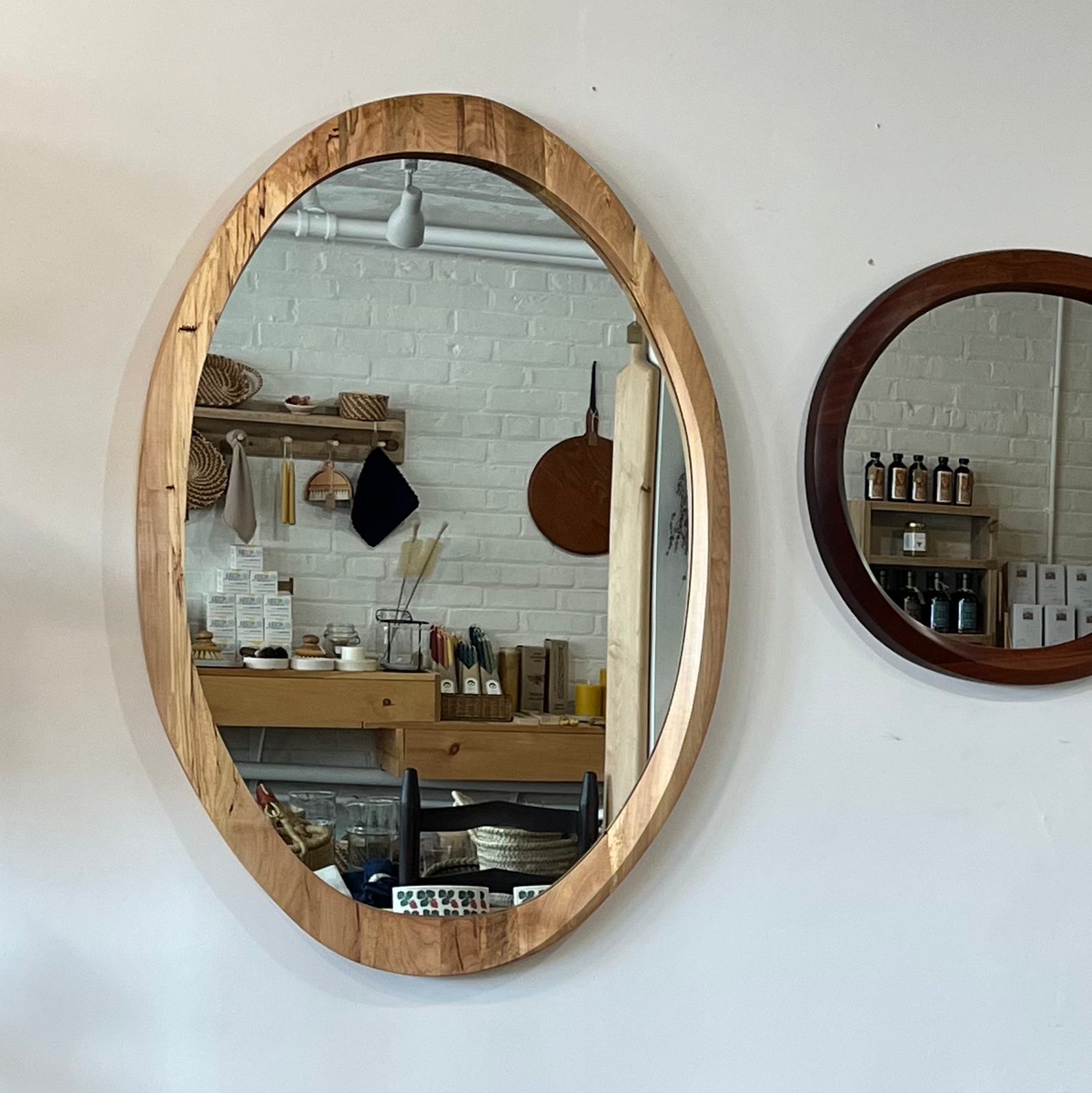 various sizes of hand-carved wooden wall mirrors each with one-of-a-kind organic shape and curves shown in butternut cherry and walnut