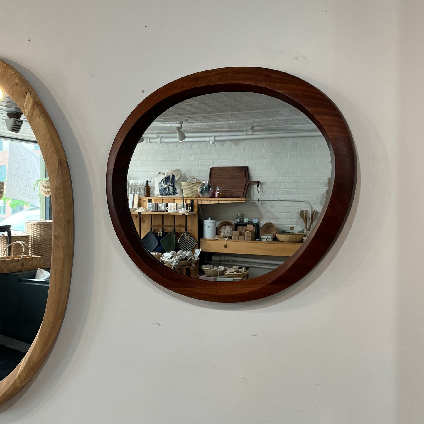 various sizes of hand-carved wooden wall mirrors each with one-of-a-kind organic shape and curves shown in butternut cherry and walnut