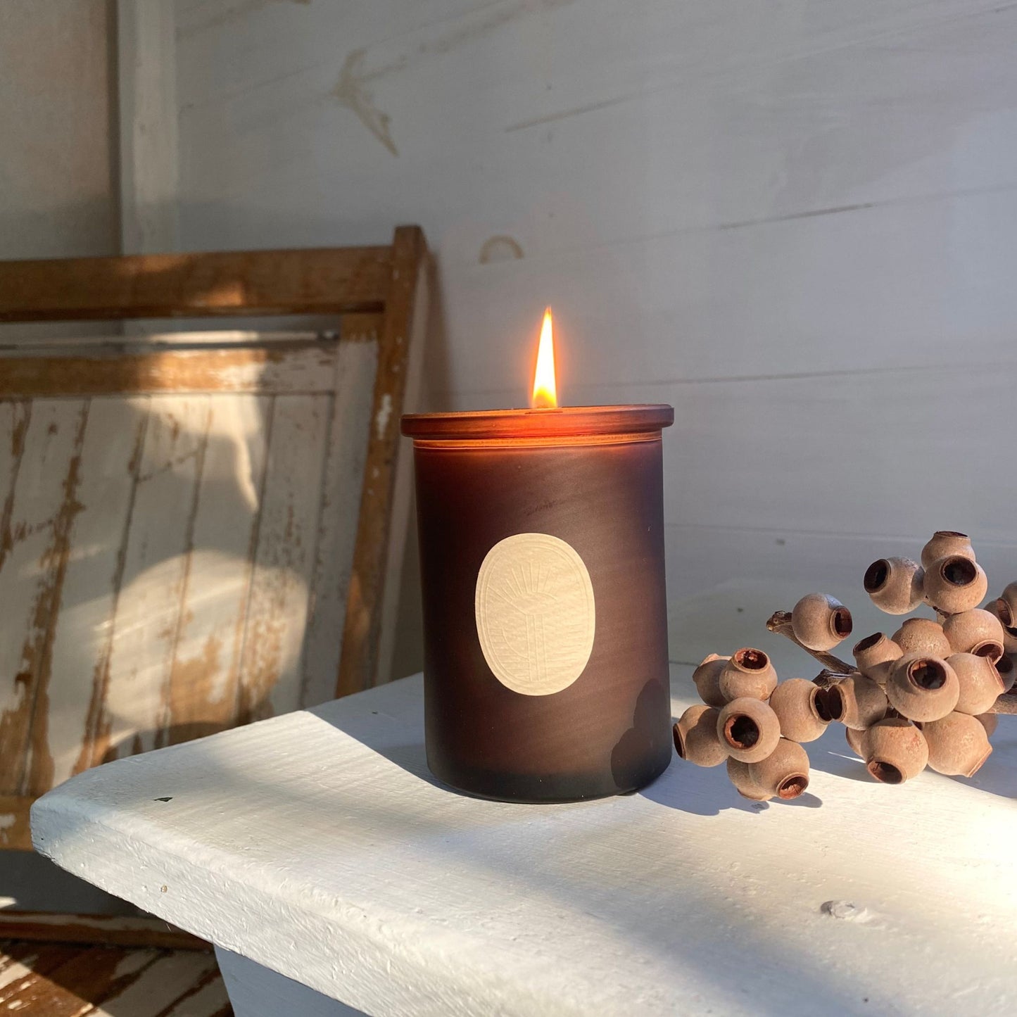 Arboretum Essential Oil Candle on a shelve with a chair in the back