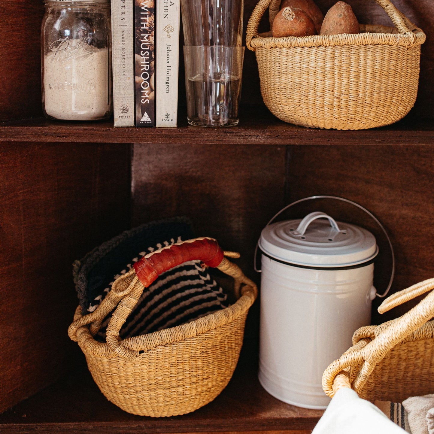 Mini bolga basket holding pot holders in a kitchen cabinet