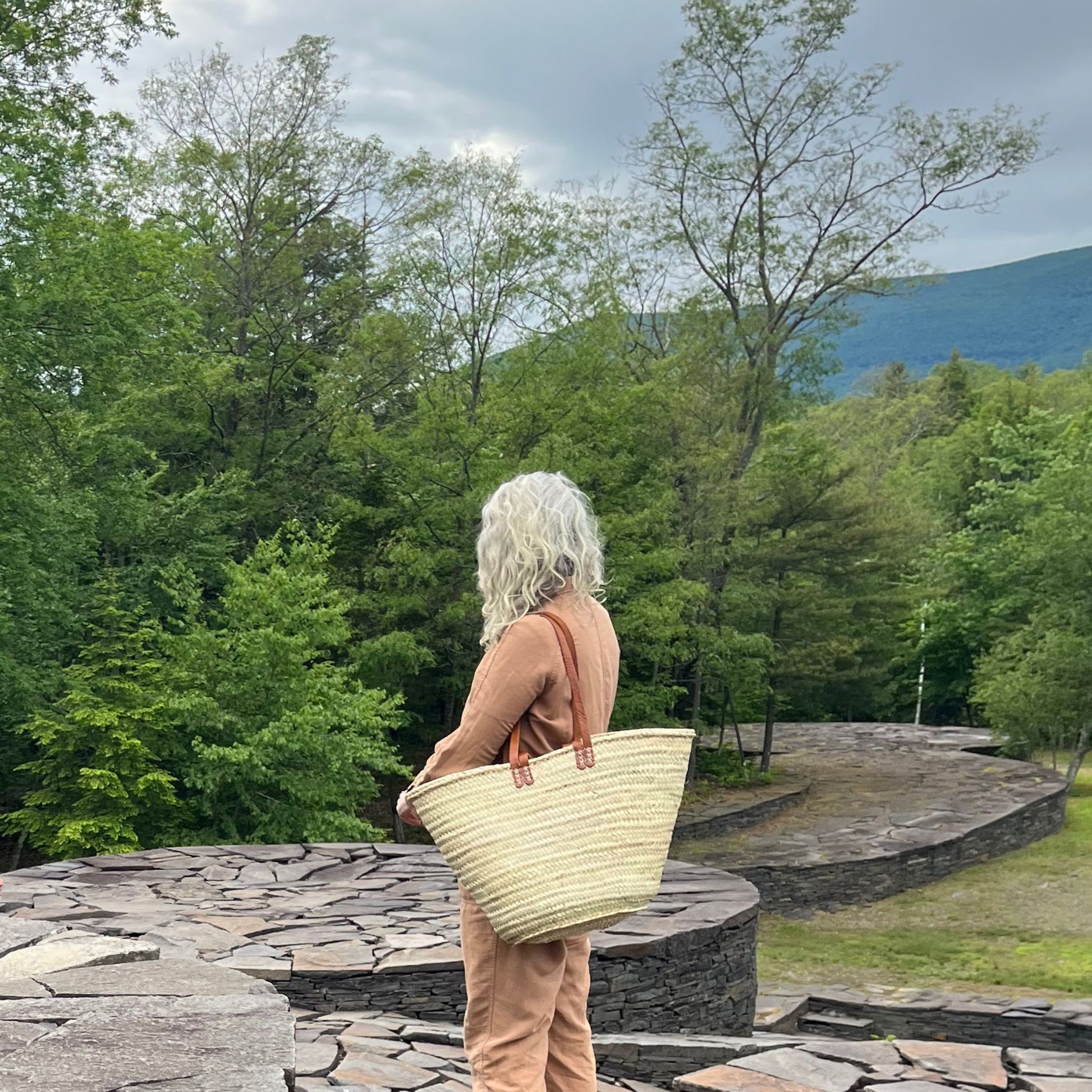 A woman carrying a french market tote bag with leather straps