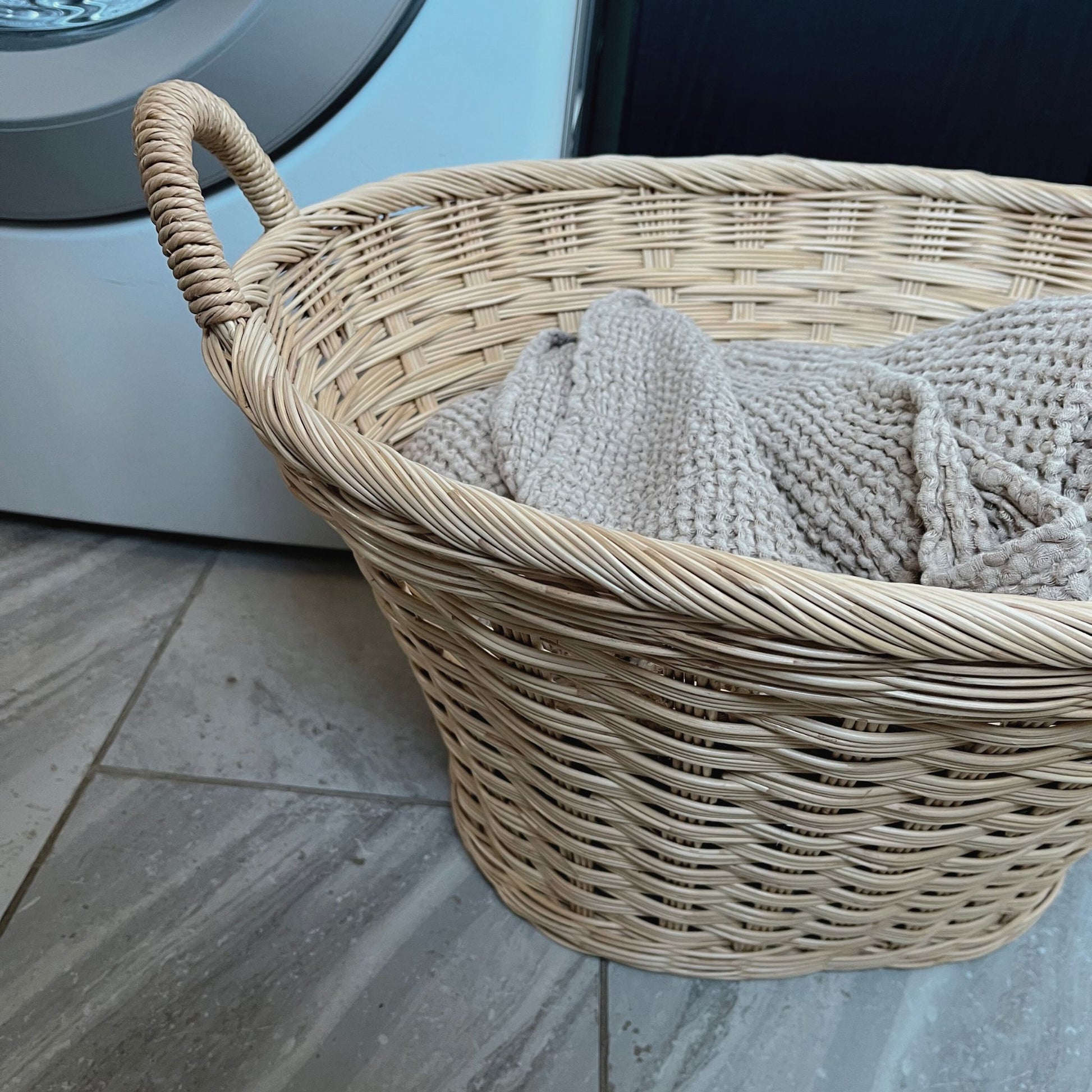 rattan laundry basket filled with linens in a laundry room