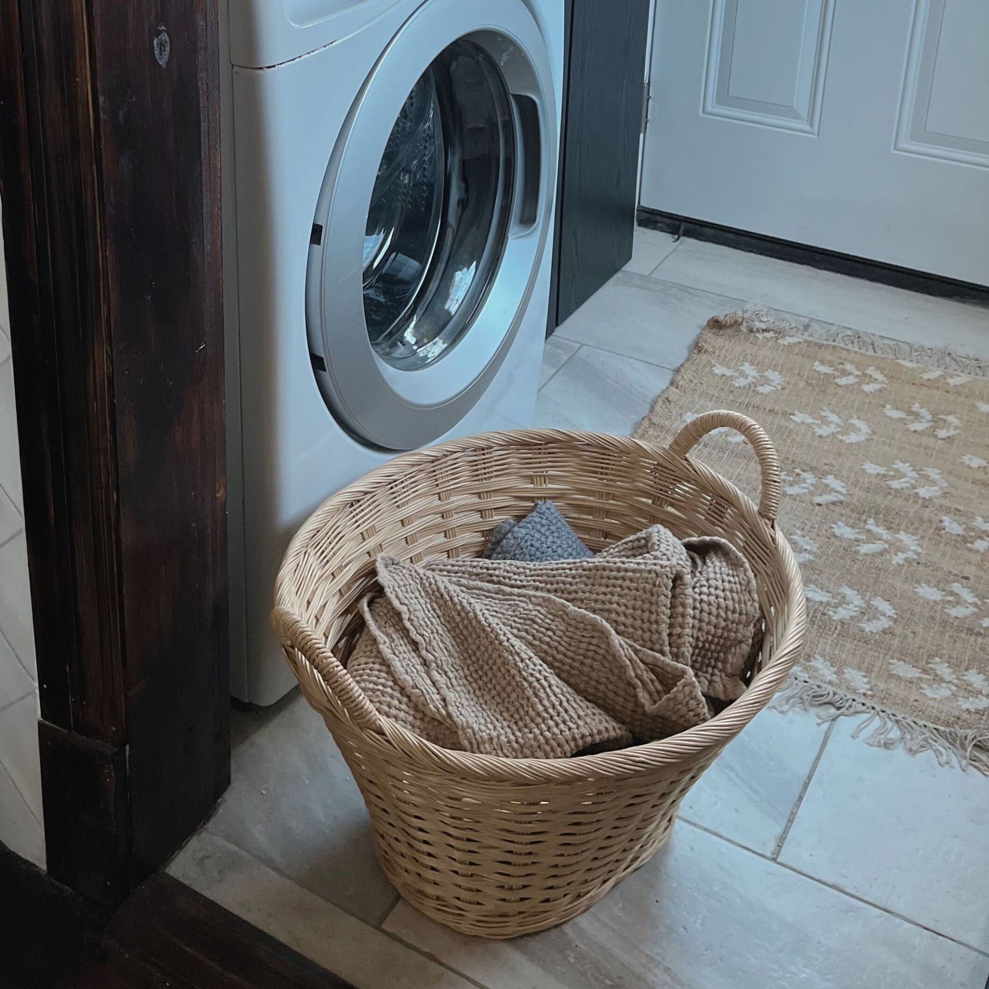 rattan laundry basket filled with linens in a laundry room