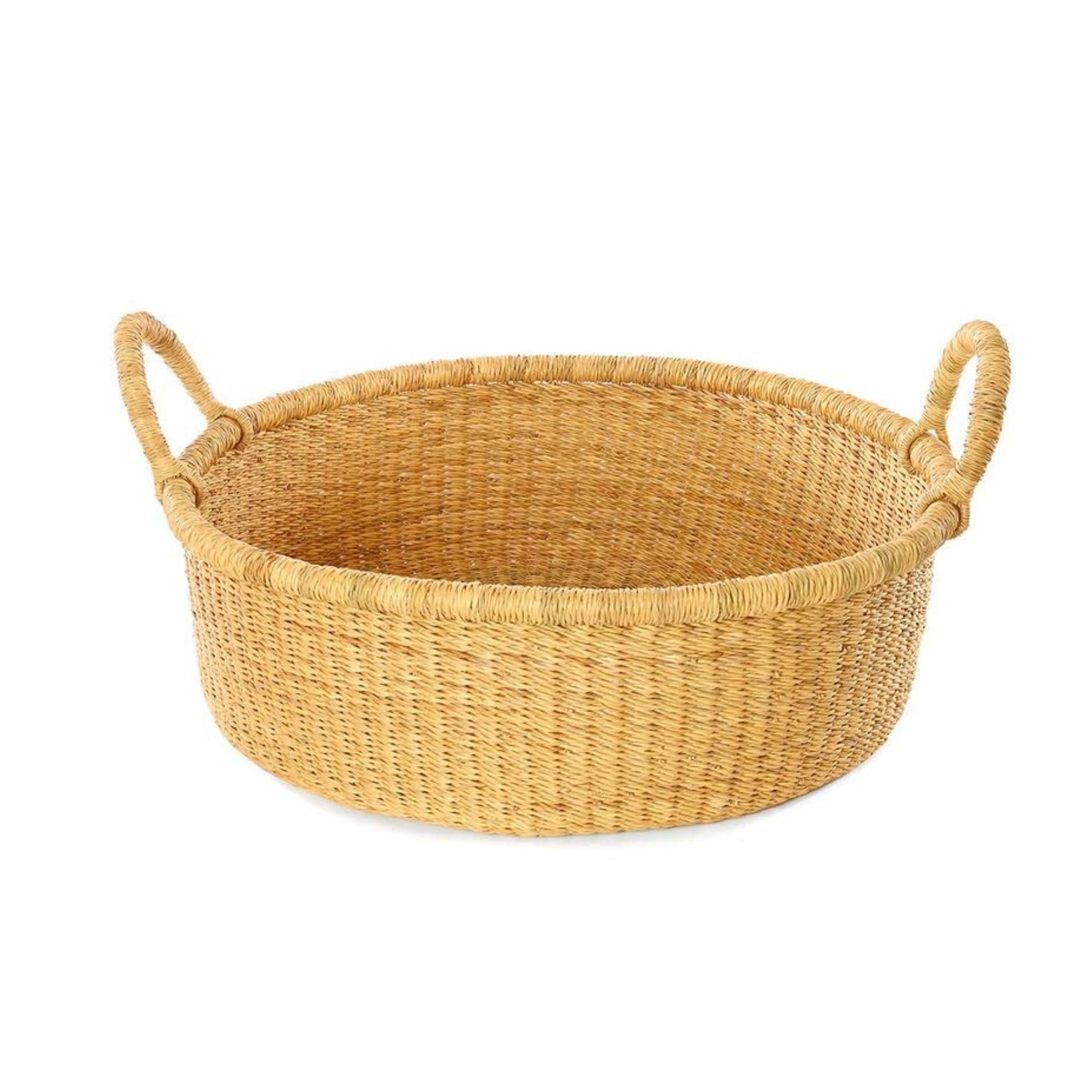 A shallow, tan, woven storage basket with handles.