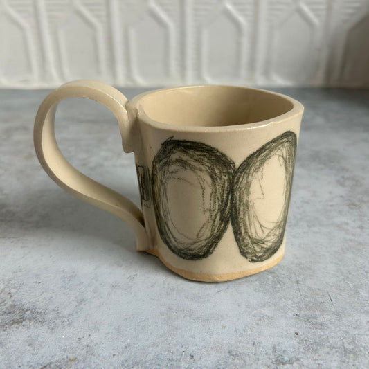 White mug with black drawn circles all around it.