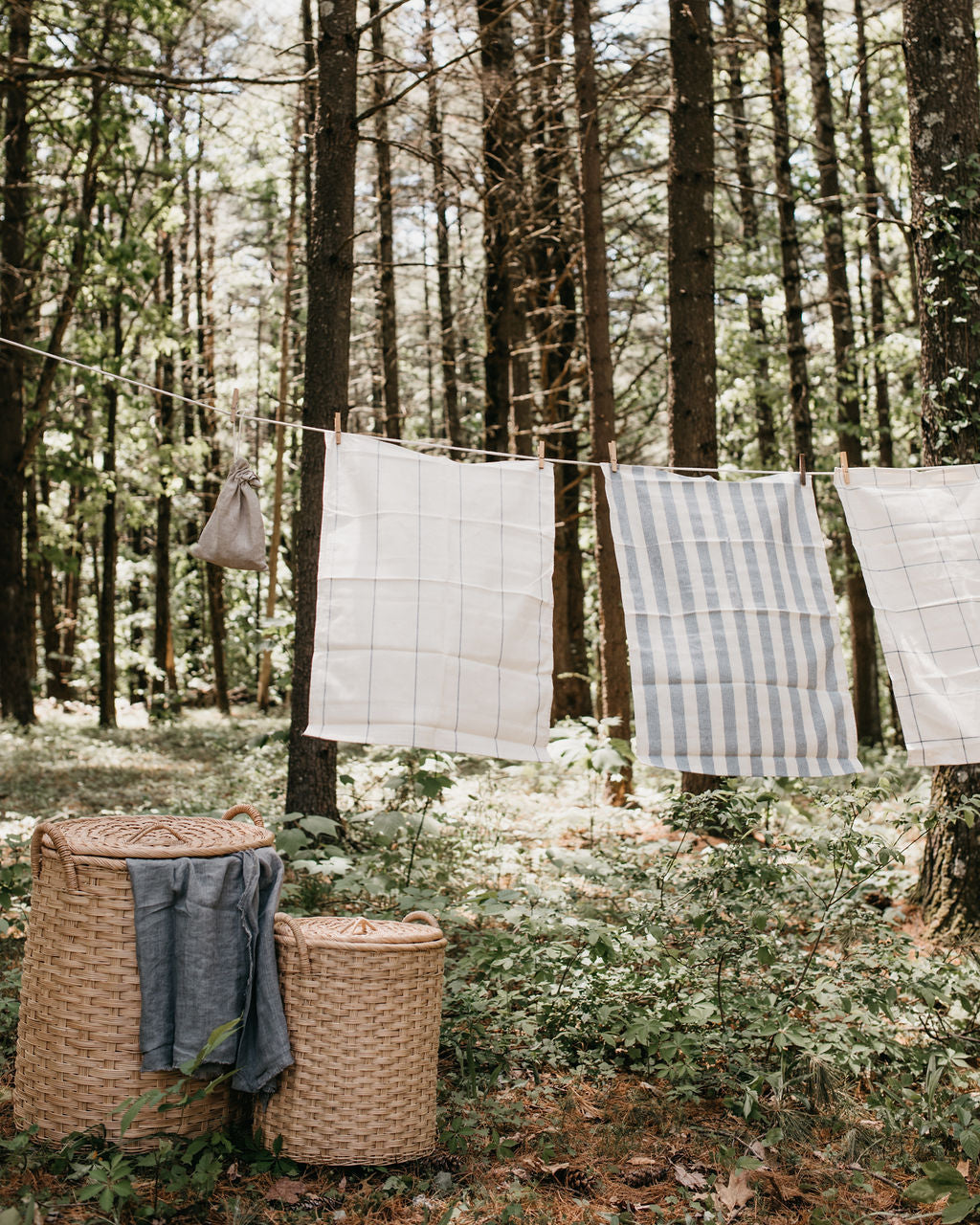 Lidded rattan storage baskets with handles shown in use outdoors with clothesline