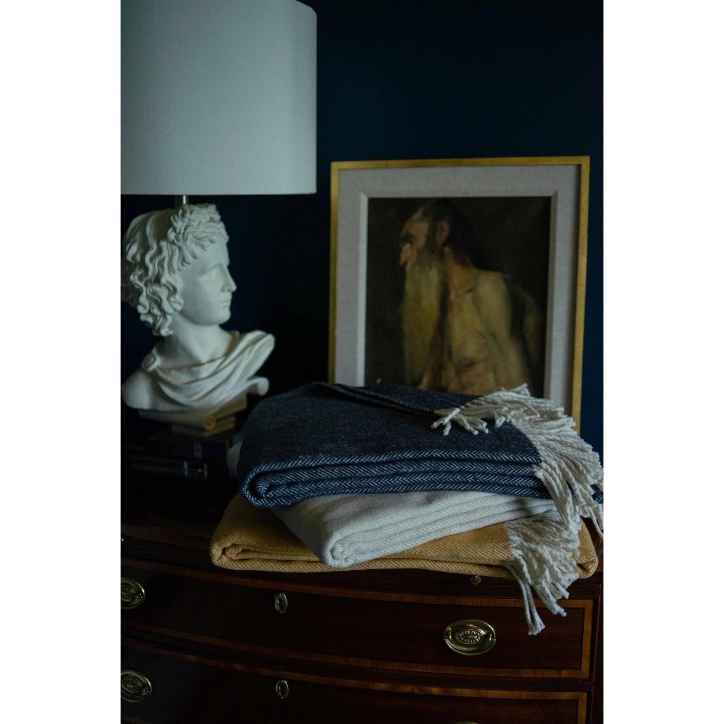 Close-up of stack of folded brushed cotton throw blankets with herringbone pattern in various colors