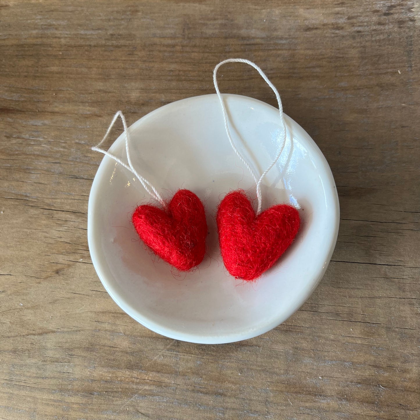 Handmade felted wool red hearts in a small bowl