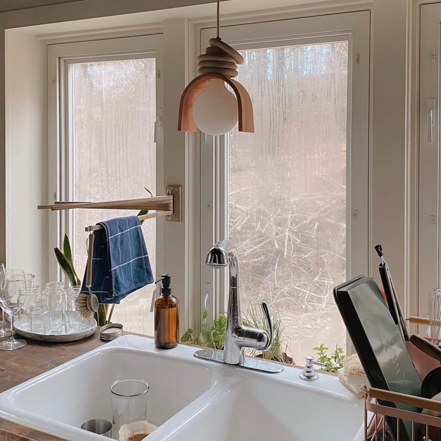 Oak wood towel drying rack with a dish brush and towel hanging from it over a kitchen sink