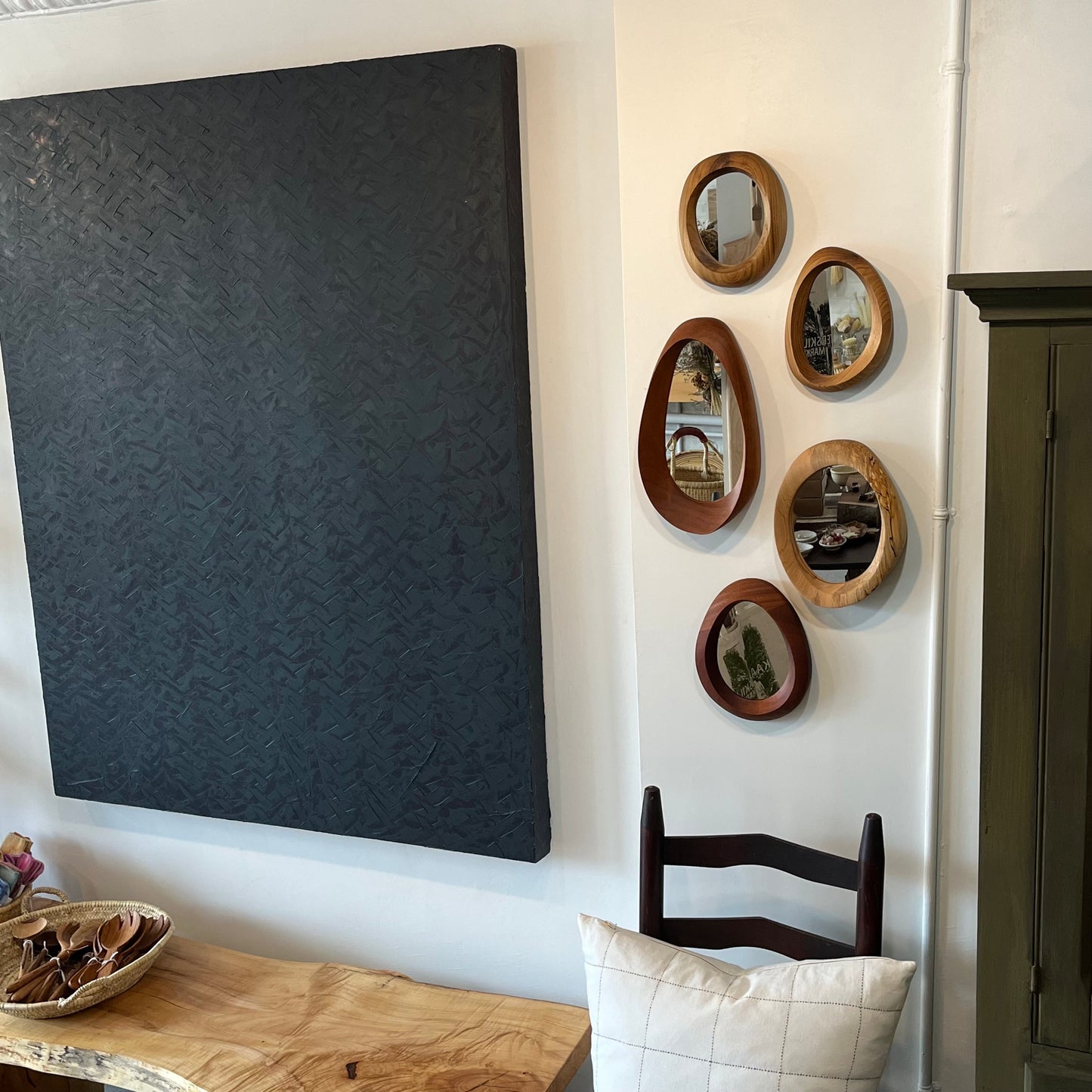 various sizes of hand-carved wooden wall mirrors each with one-of-a-kind organic shape and curves shown in butternut cherry and walnut