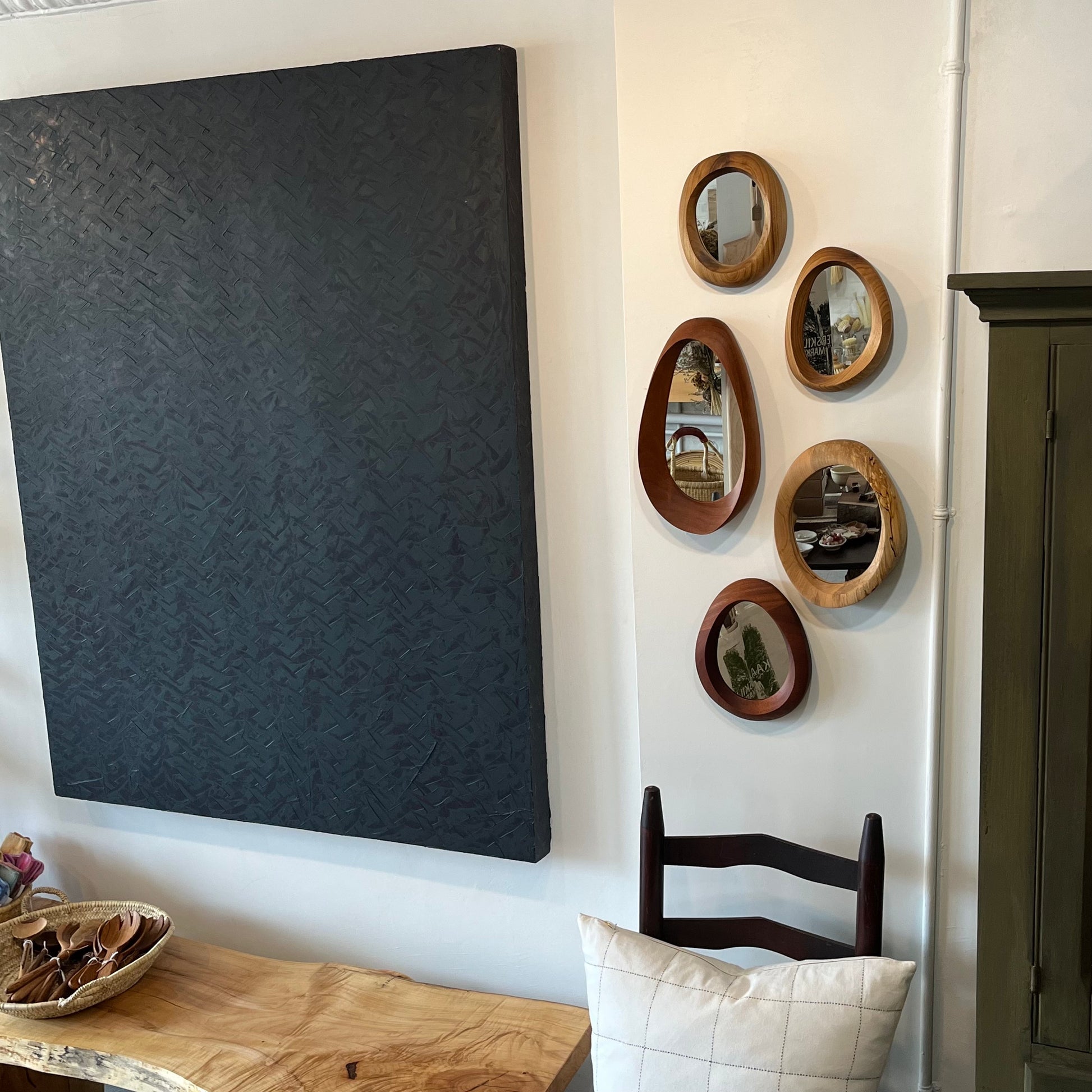 various sizes of hand-carved wooden wall mirrors each with one-of-a-kind organic shape and curves shown in butternut cherry and walnut