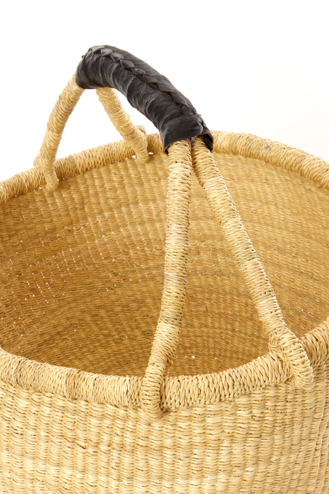 Close up of a large bolga basket with a black leather handle