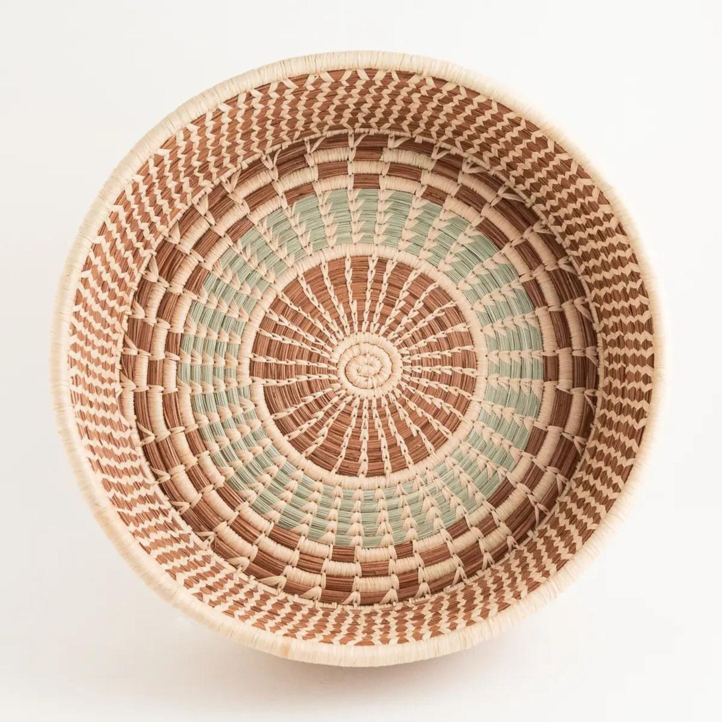 An above shot of a brown, tan, and light green handwoven pine needle harvest basket.