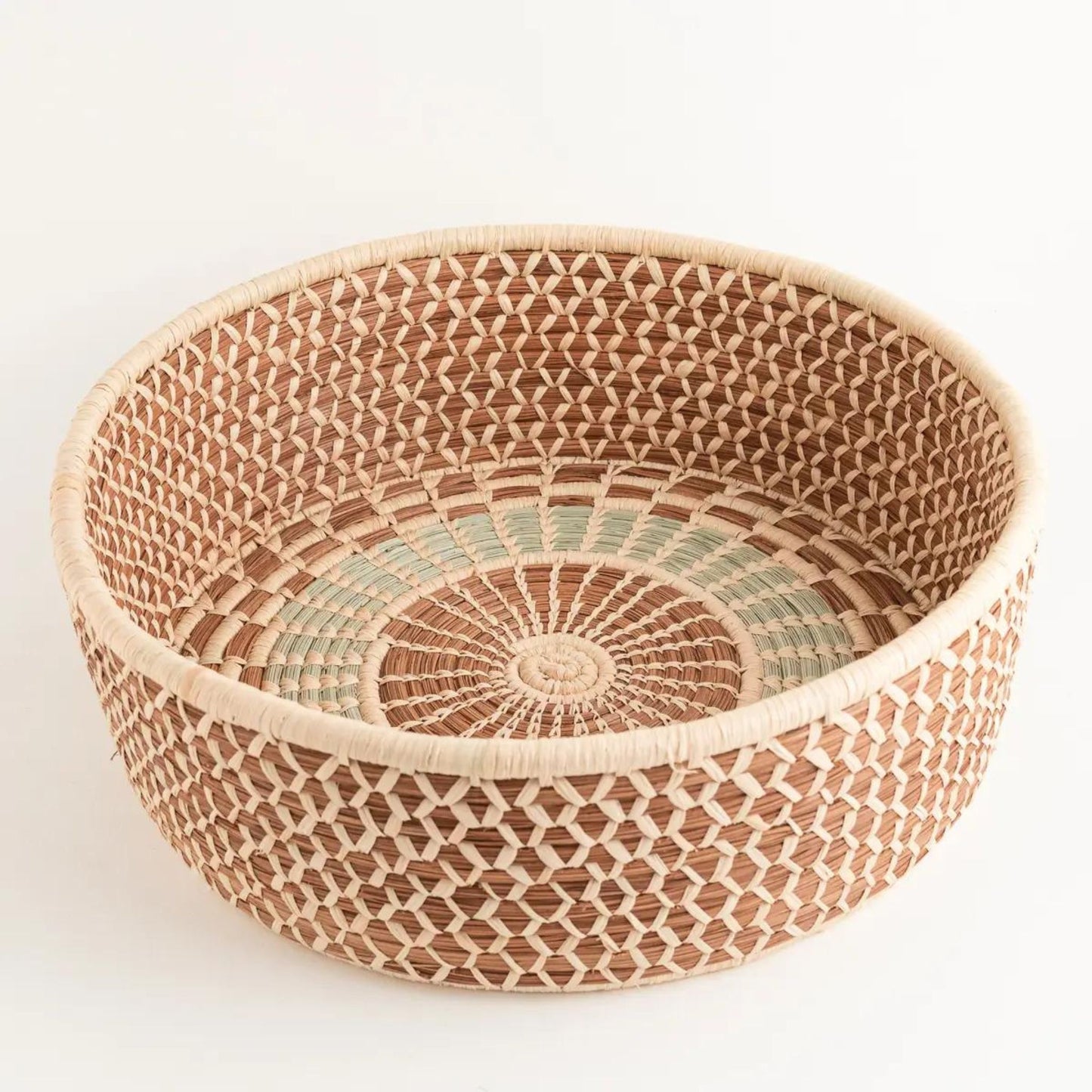 A brown, tan, and light green handwoven pine needle harvest basket.