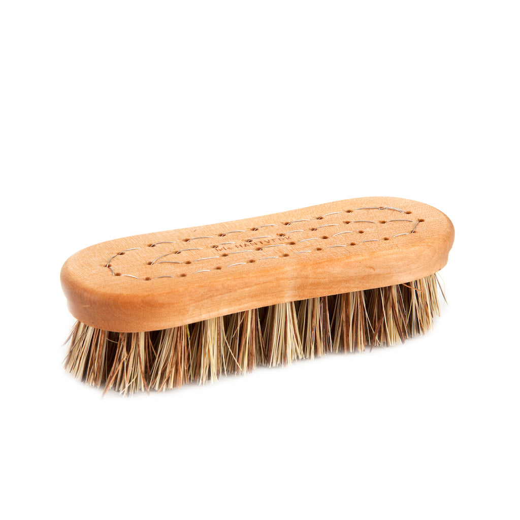A vegetable scrub brush with a birch wood handle and strong water-resistant plant fibers.