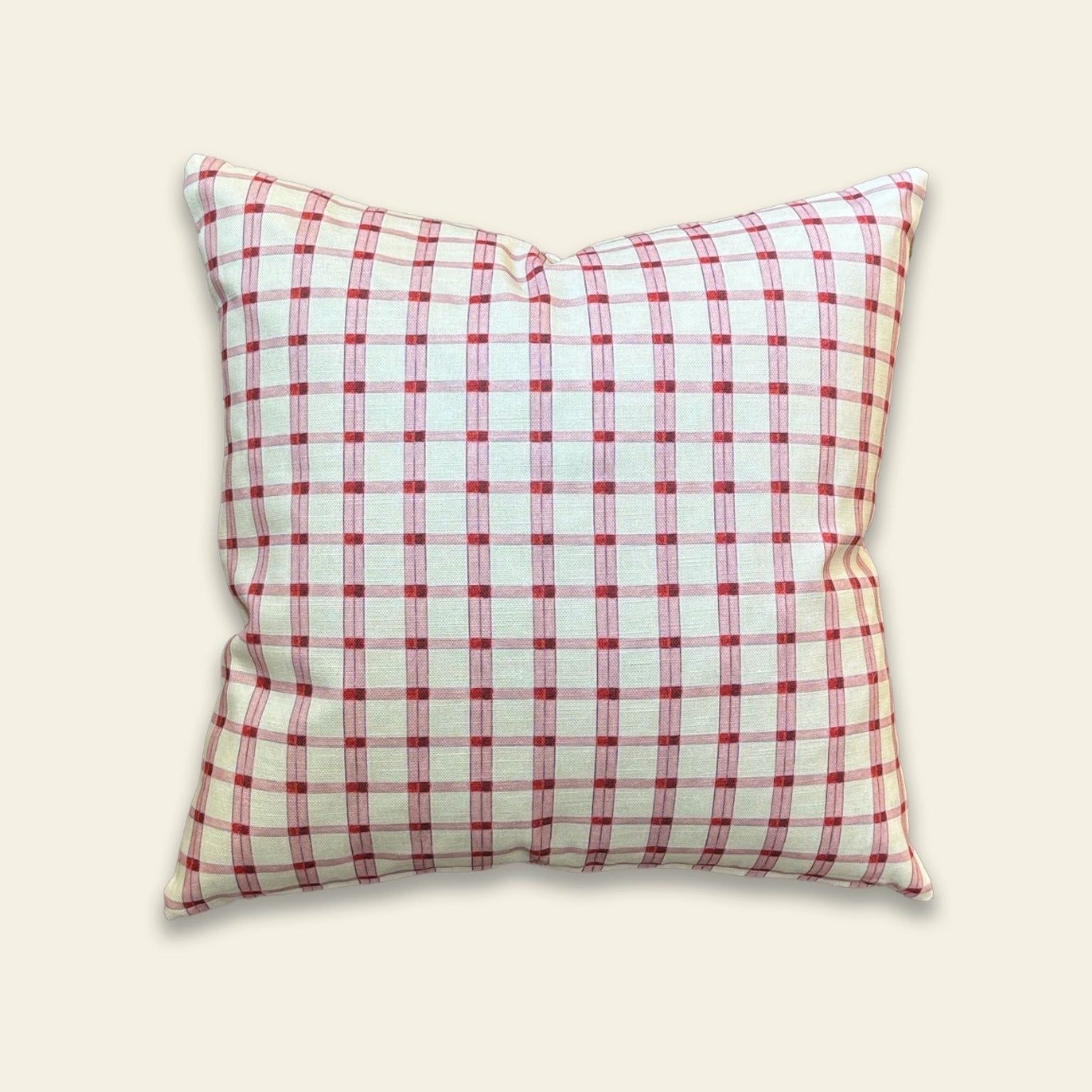 A square throw pillow with a red and white gingham checkered pattern, shown against a solid light beige background.