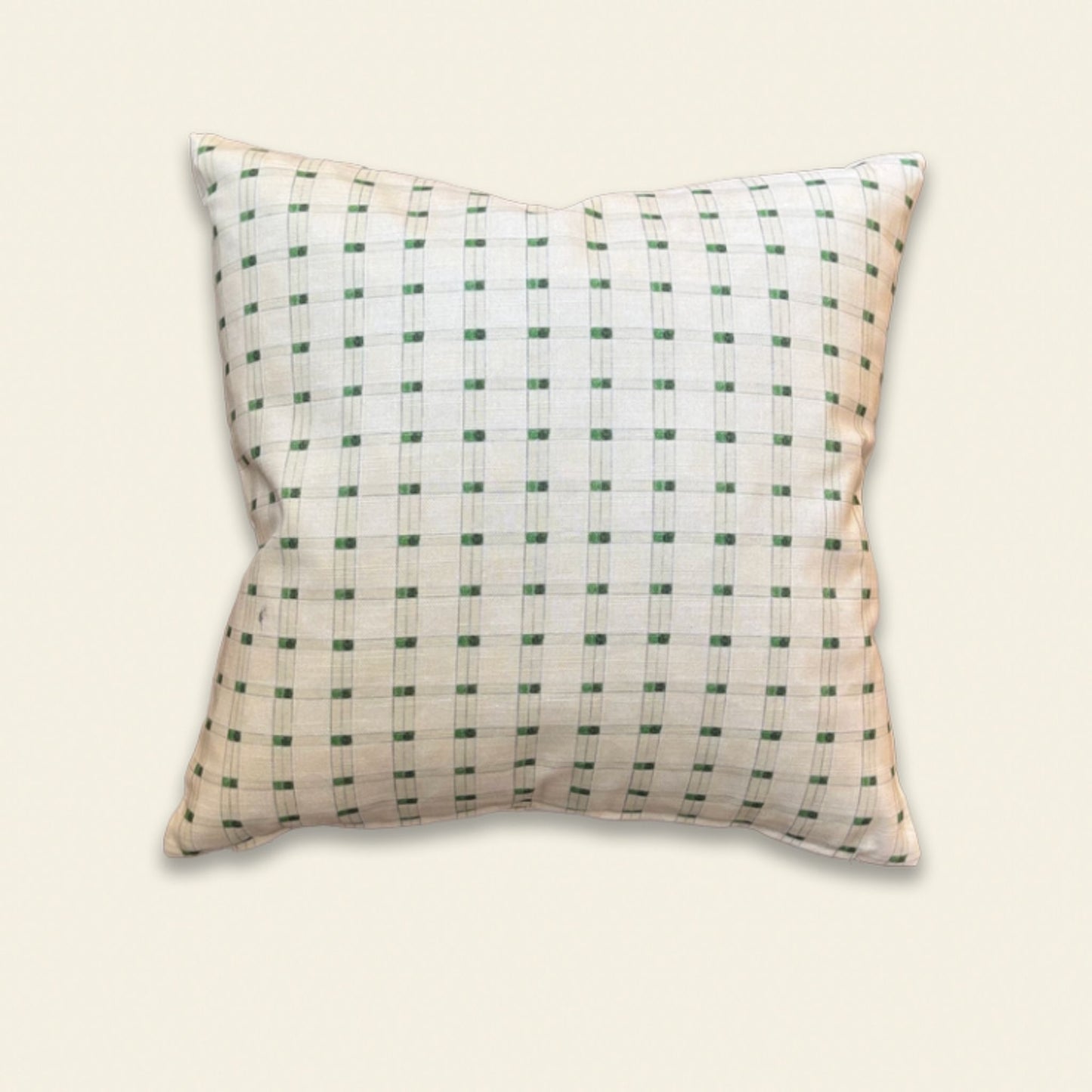 A square decorative throw pillow with a white base and a green grid pattern, shown against a solid light beige background.