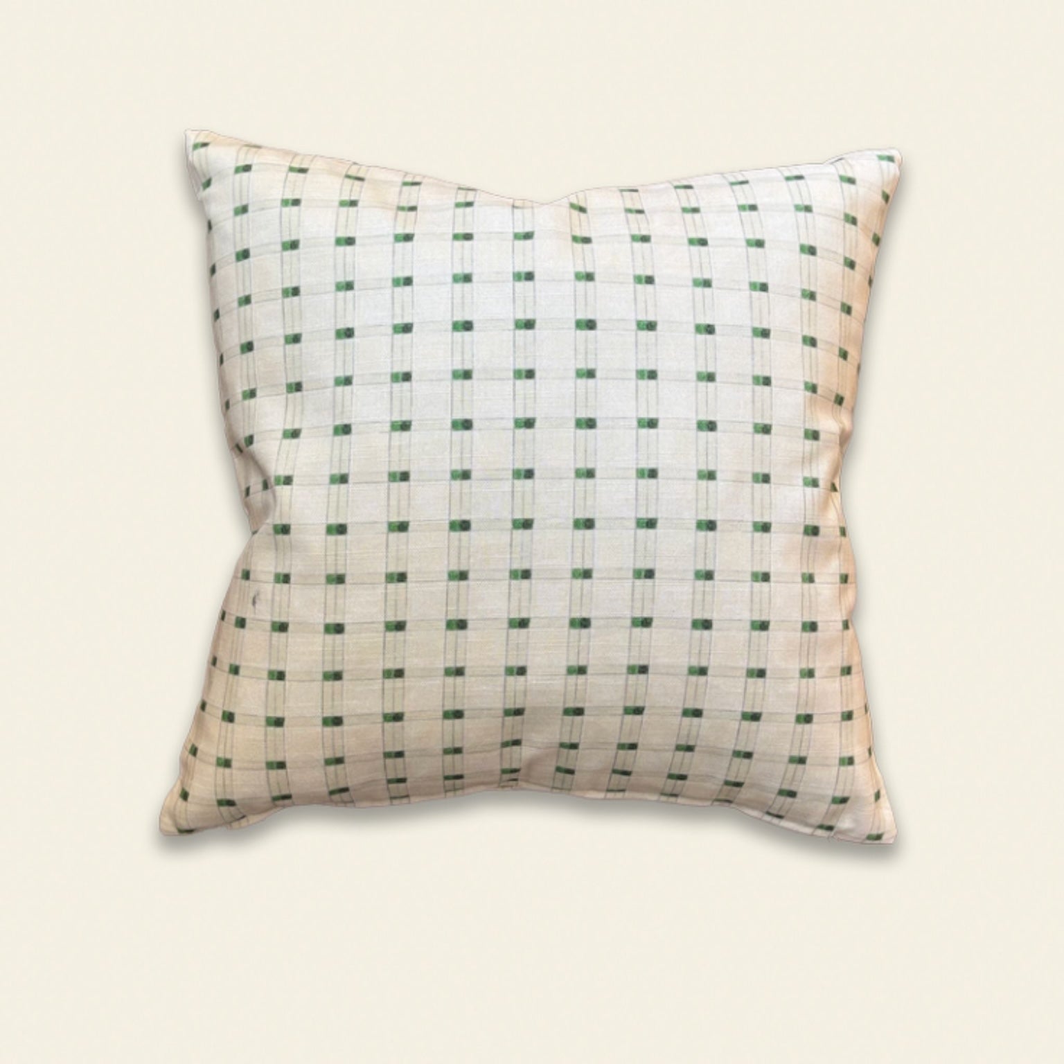 A square decorative throw pillow with a white base and a green grid pattern, shown against a solid light beige background.
