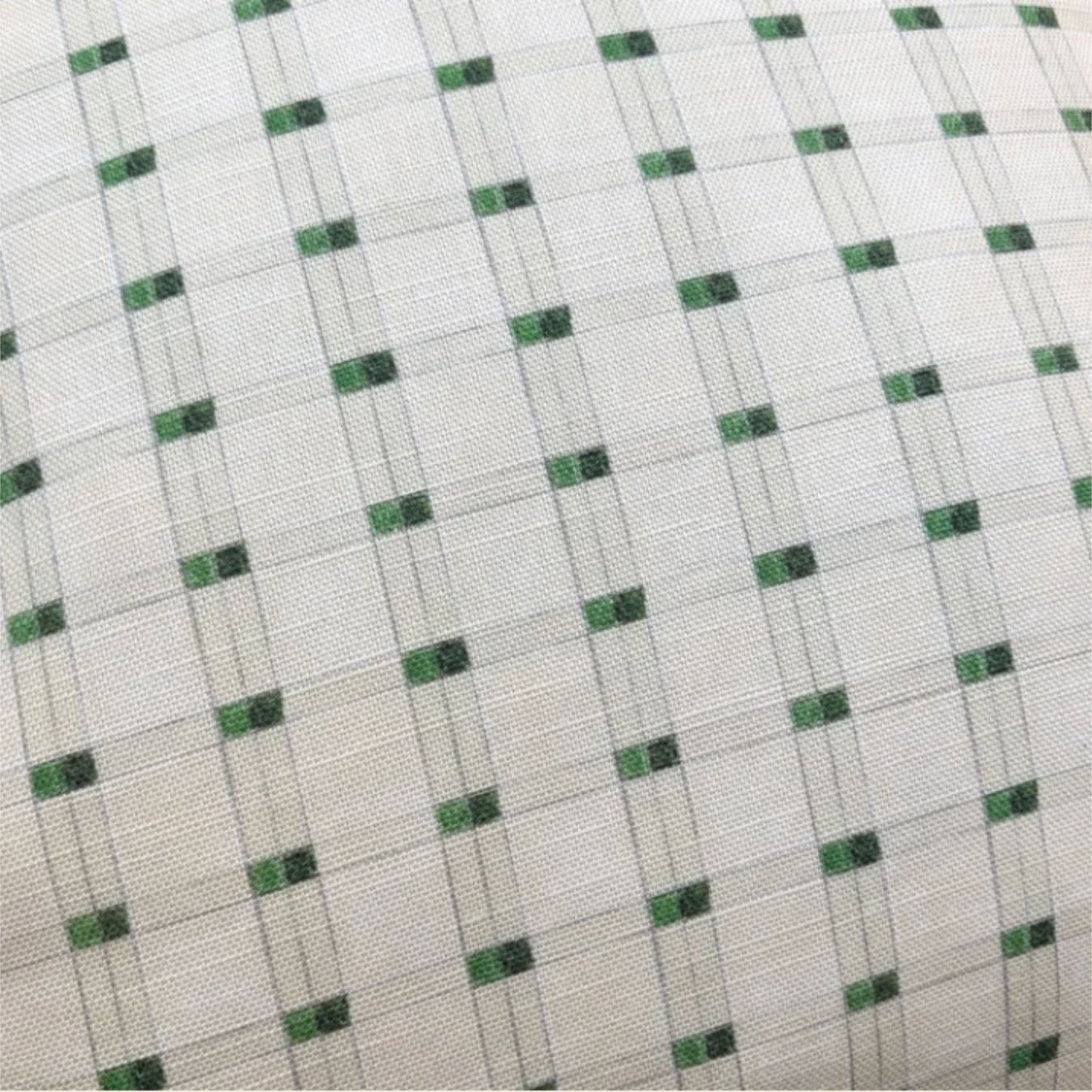 A close-up of a woven fabric with a white base, featuring a repeating pattern of small green squares outlined by thin gray intersecting lines.