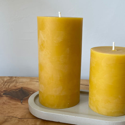 Closeup of Two beeswax candles of different sizes on a ceramic plate