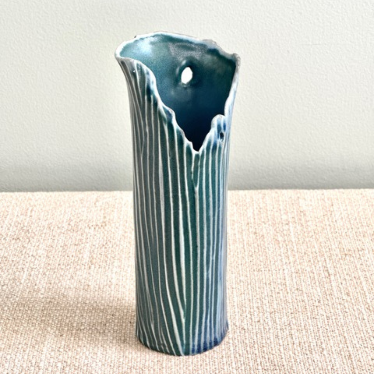 Blue ceramic vase with textured design on a beige surface