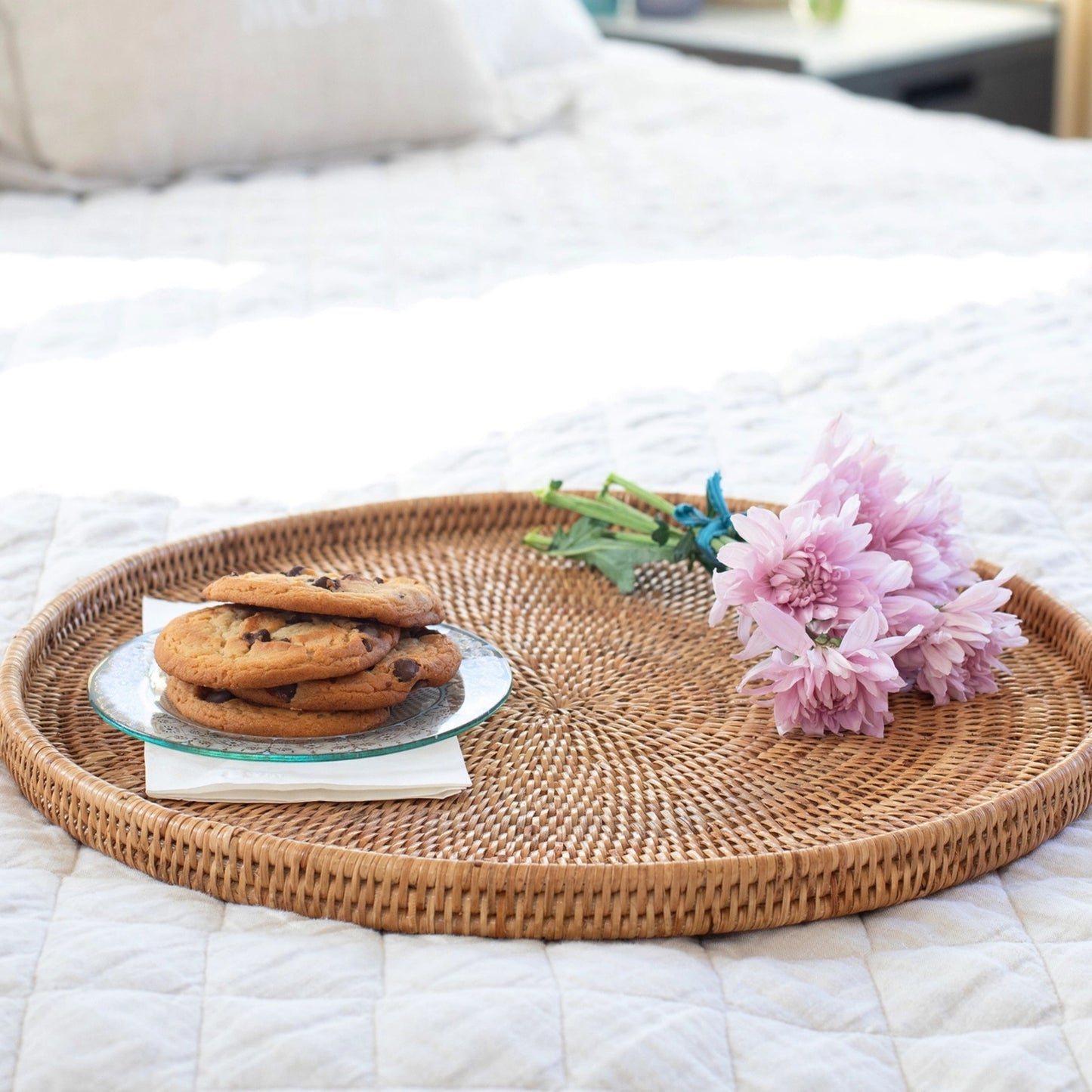 Wicker tray with cookies and flowers on a bed