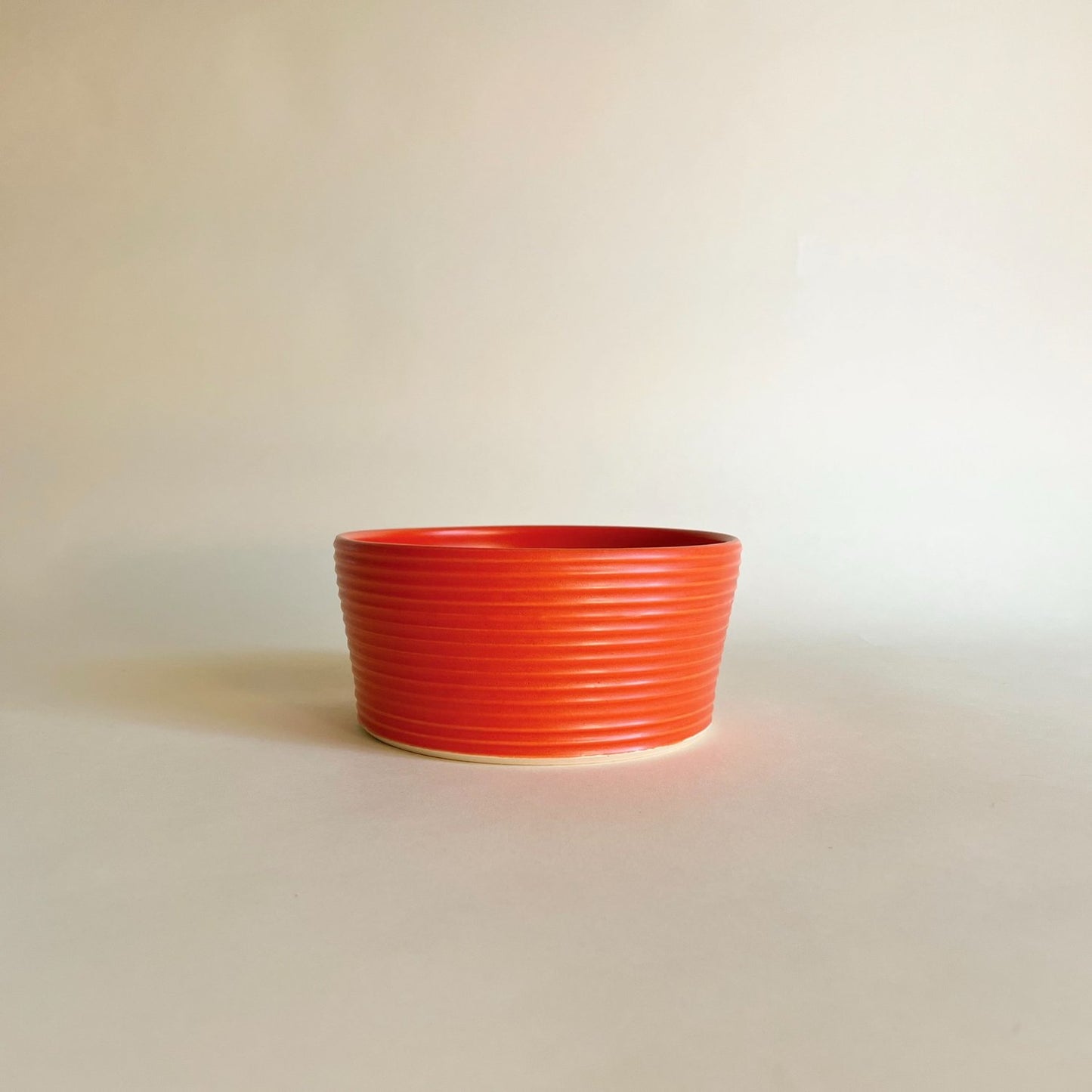 Wheel-thrown ribbed ceramic stoneware dinner bowl with handmade glaze in red color. 6" x 2.5"