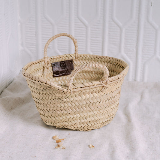 Woven basket with a handle on a textured white background