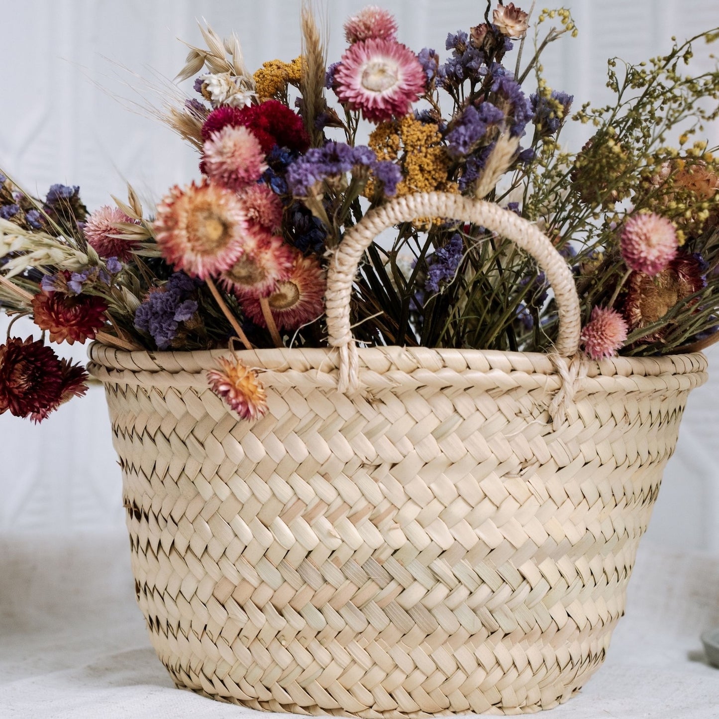Woven basket filled with dried flowers on a white background