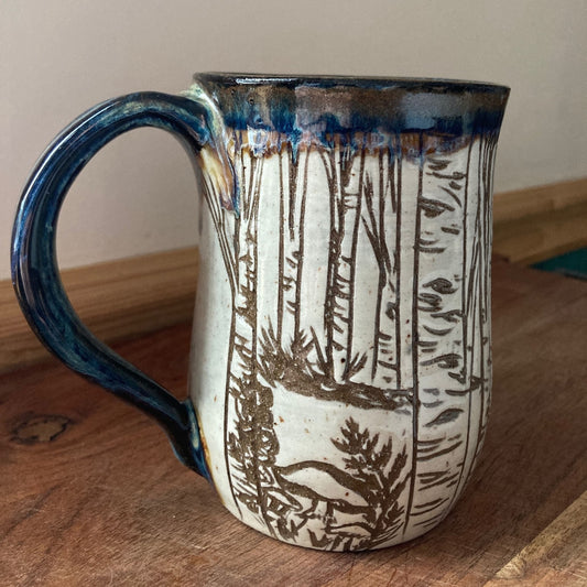 Ceramic mug with nature-themed design on a wooden surface