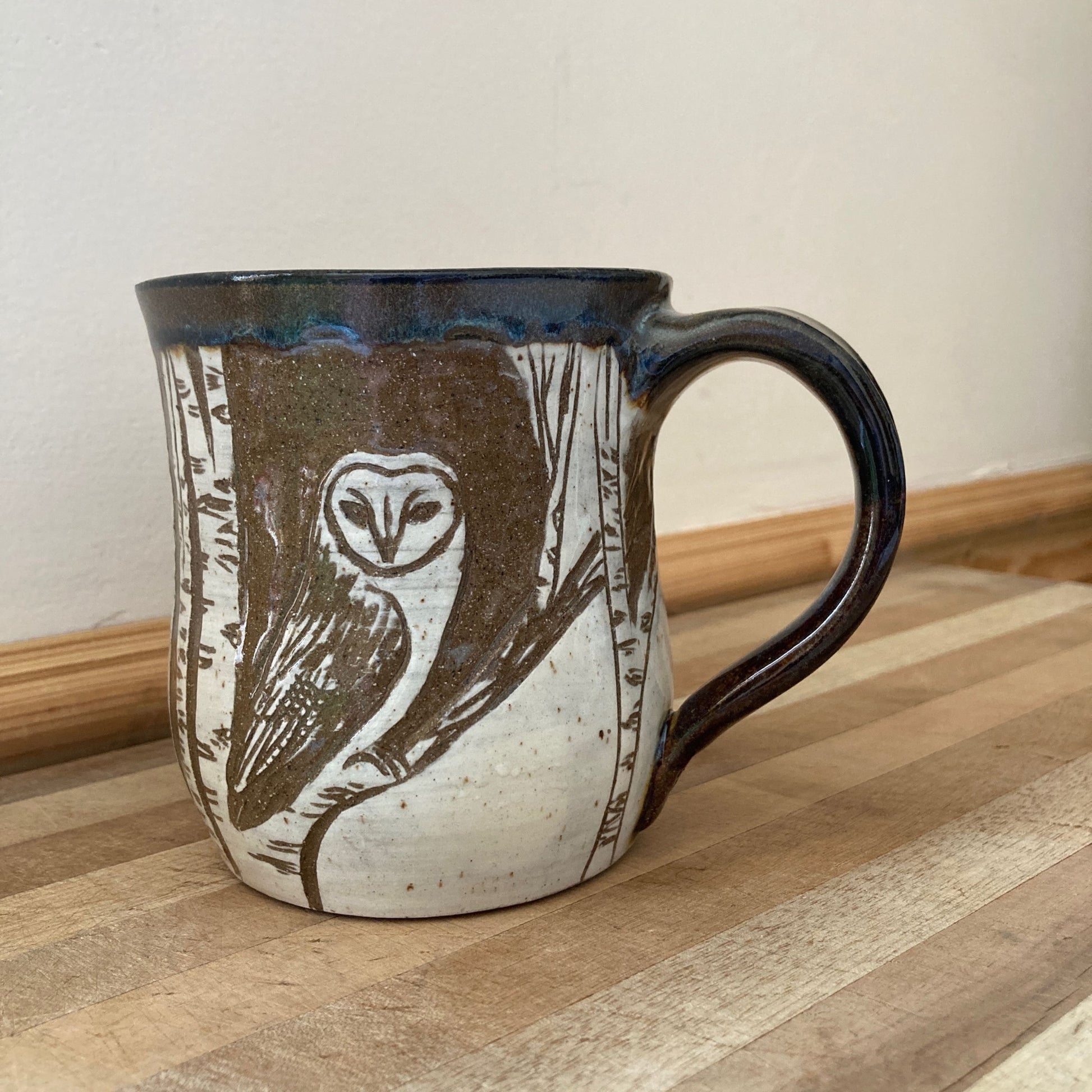 Ceramic mug with owl design on a wooden surface