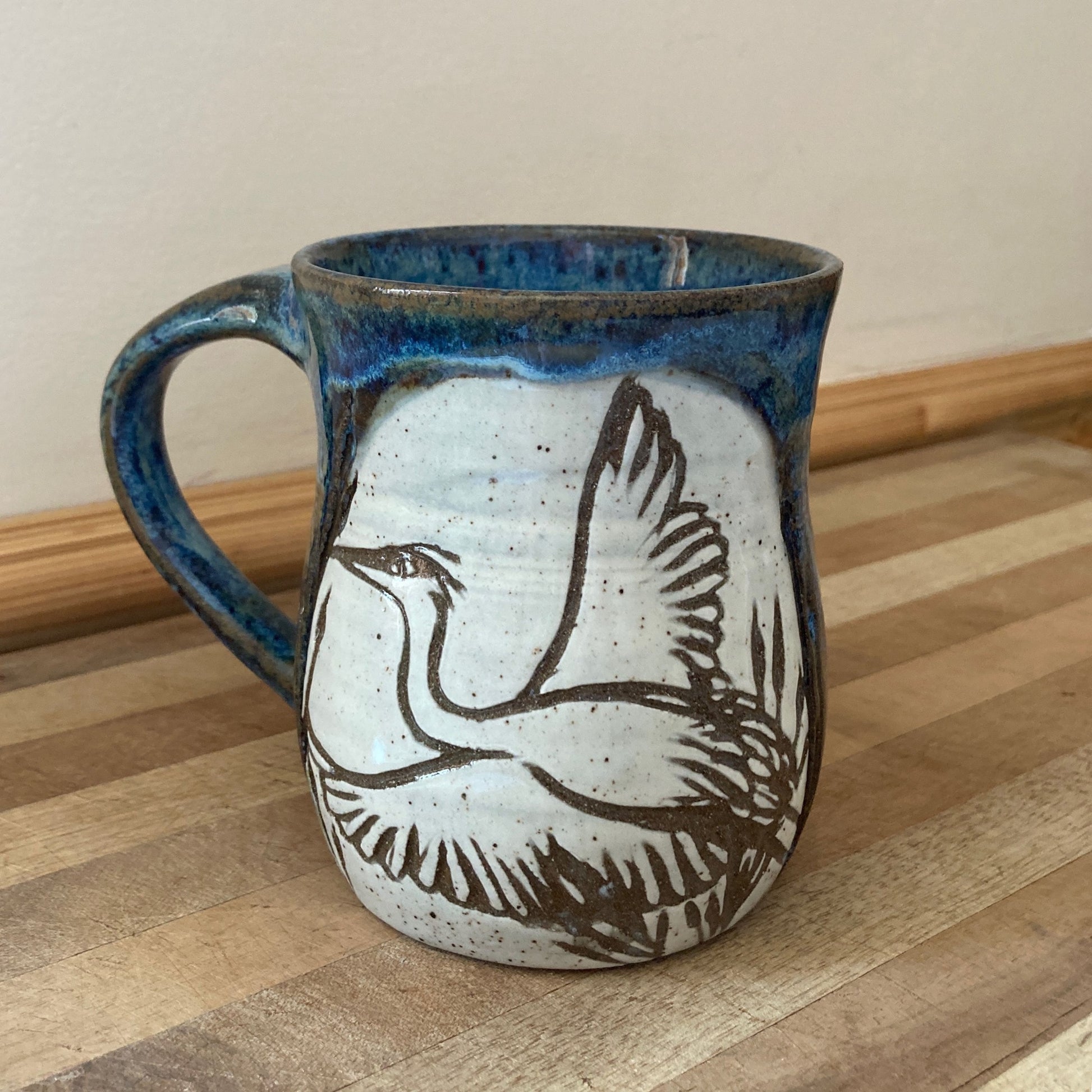 Ceramic mug with a bird design on a wooden surface
