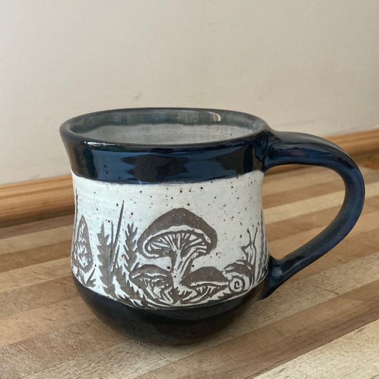 Ceramic mug with nature-themed design on a wooden surface