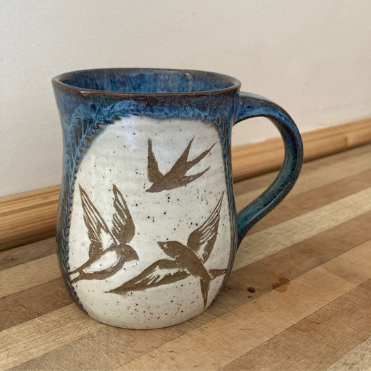 Ceramic mug with bird designs on a wooden surface