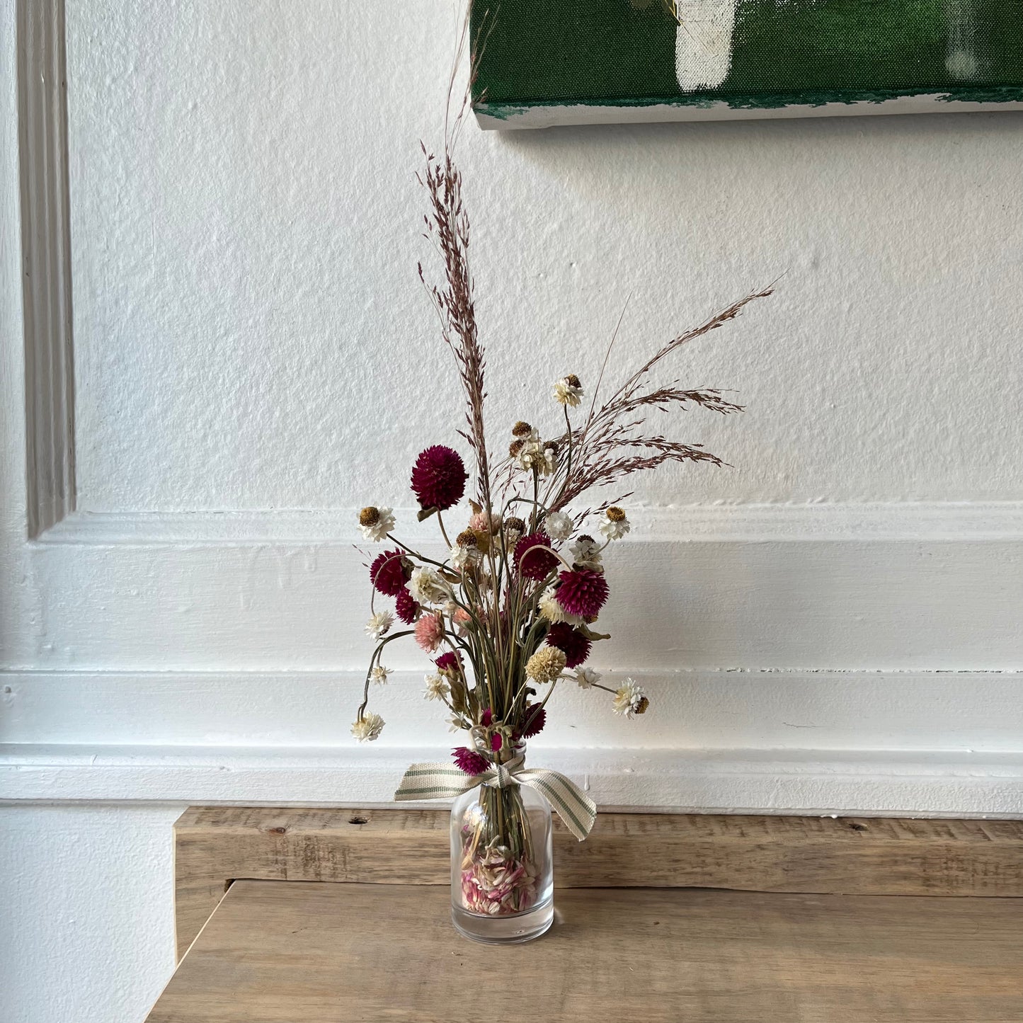 Locally dried flowers in a glass bud vase tied off with a striped cotton ribbon.  Approximate Flower Height: 9 inch; Glass Width: 2 inch