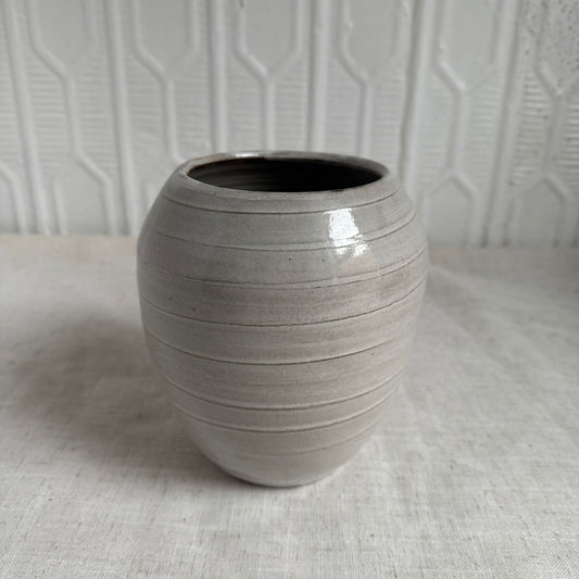 Gray ceramic vase on a textured surface with a light gray background