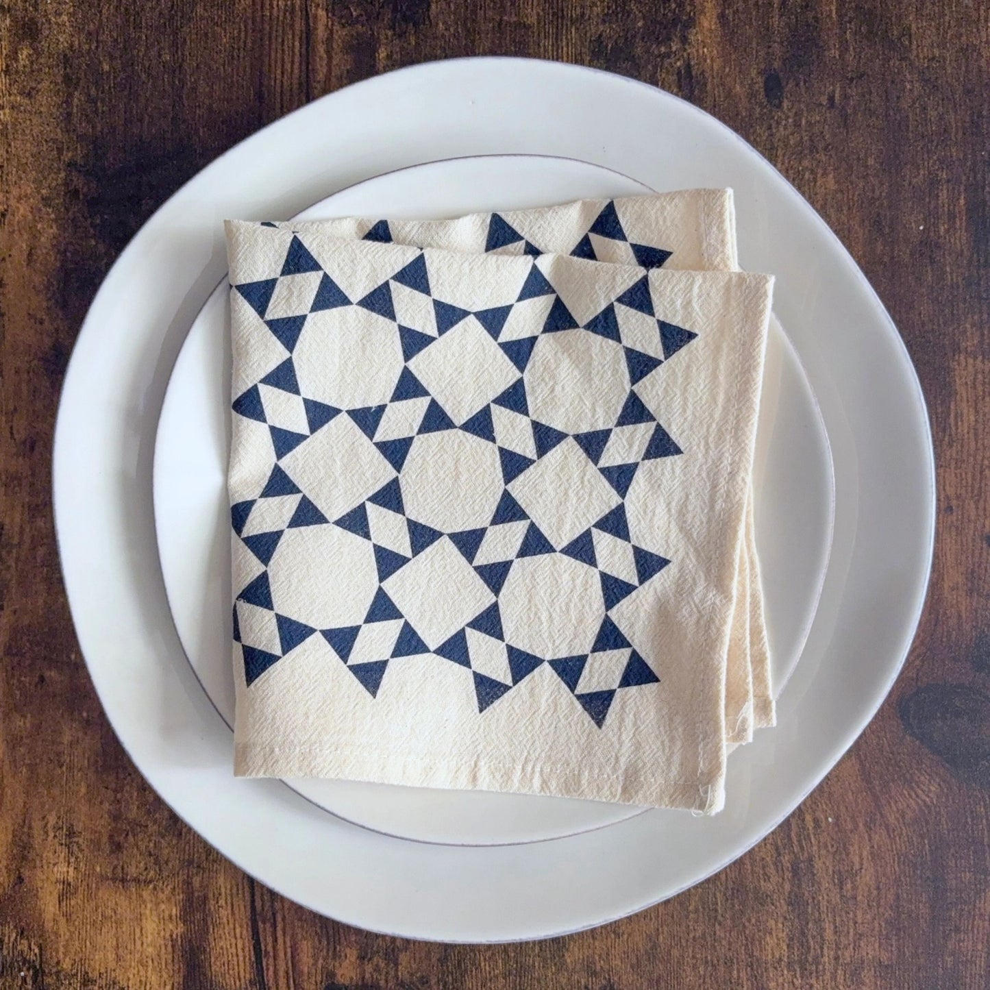 Folded napkin with blue geometric pattern on a white plate on a wooden table