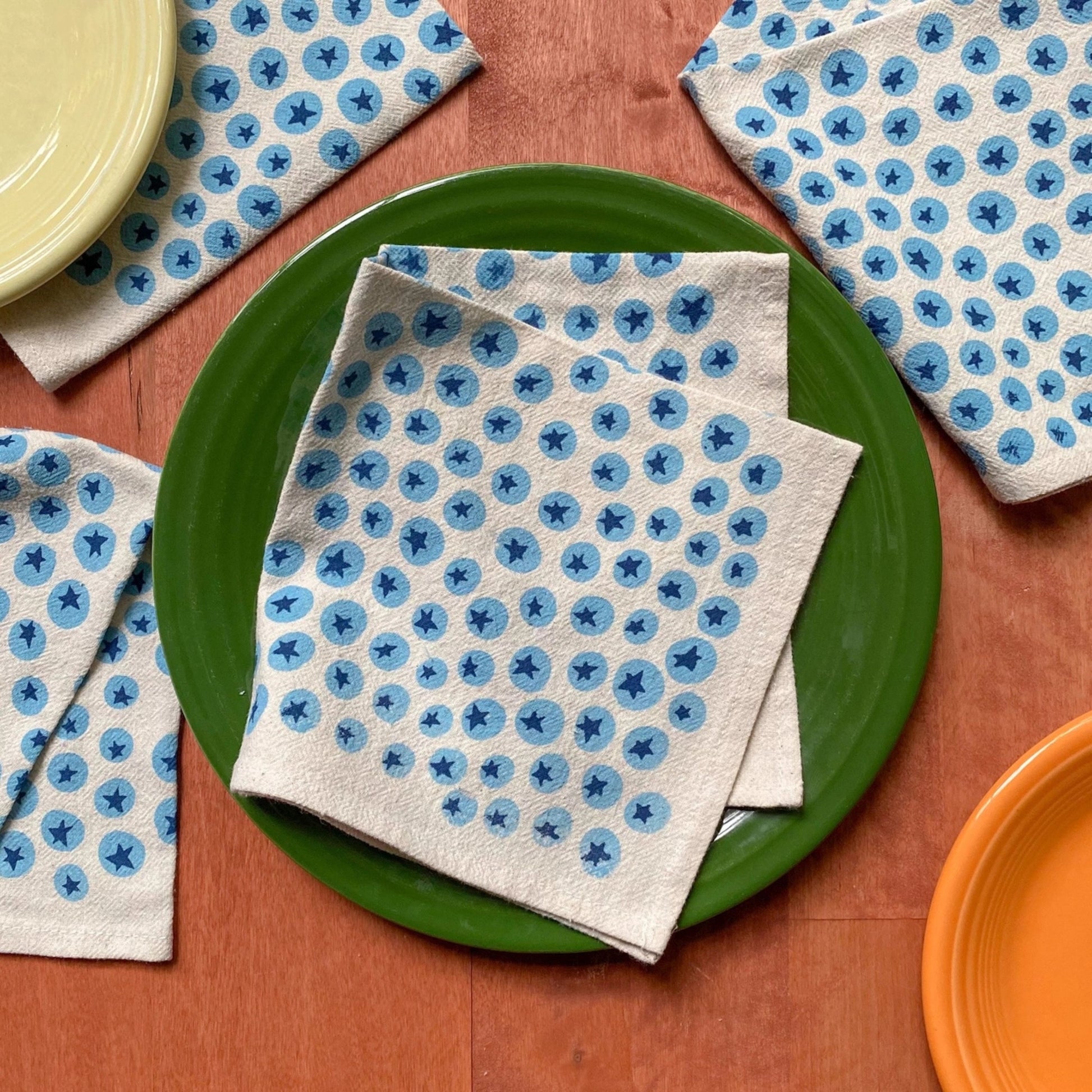 Stack of white cloth napkins with blueberry pattern on a wooden surface
